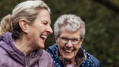 Two women walking laughing along with one another