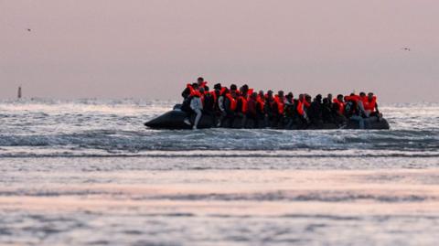  Migrants sit on a dinghy as it prepares to sail into the English Channel on July 10, 2025 in Gravelines, France.