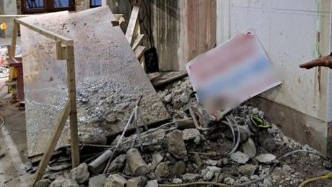 Lots of concrete rubble at an indoor building site with wooden looking slab.