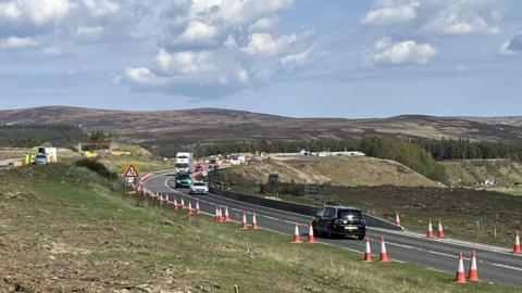 A stretch of the A9 road with a bend. There are traffic cones and signs of ground being cleared ready for new road surfaces to be laid