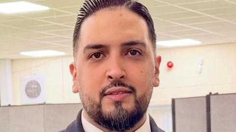 A man with short black hair and a short goatee beard. 