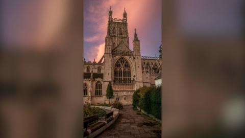 Gloucester Cathedral in front of a pink sky.