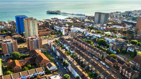 A view over homes and flats in Brighton. Brighton Pier and the sea is in the top of the image.