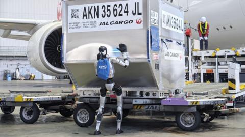 A humanoid robot pushes a cargo container during a media demonstration at Haneda airport in Tokyo on April 27, 2026. Japan Airlines will test the use of such robots at the airport from May, as the airline aims for their practical use in ground handling tasks, such as cargo loading and unloading, in 2028 amid a chronic manpower shortage
