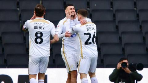 Aaron Collins of MK Dons (centre) celebrates