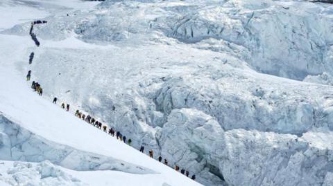 Climbers walk in a long queue as they head to summit Mount Everest in the Solukhumbu distric