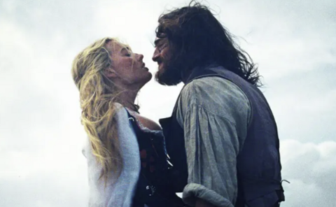 Margot Robbie and Jacob Elordi in character in the film. They are locked in a passionate embrace on the wind-swept moor.