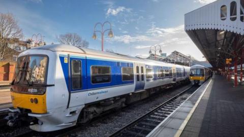 Two Chiltern Railways trains at a station platform in red, yellow and white livery.