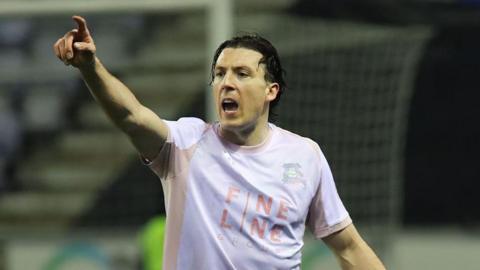 Alex Mitchell points with authority and barks orders to his defence, wearing Plymouth Argyle away pink and brown kit