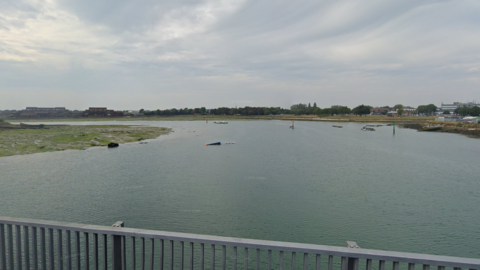 A Google Maps picture of Haslar Lake, which has grass surrounding it and boats on it.