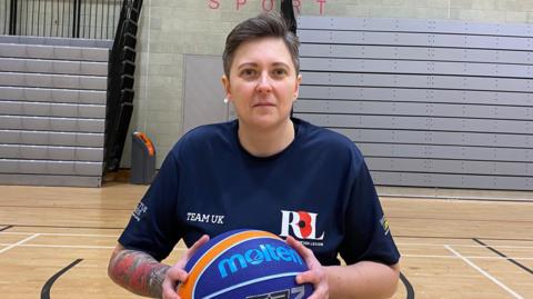 Liz Lee holding a basketball and wearing a navy Team UK t shirt 