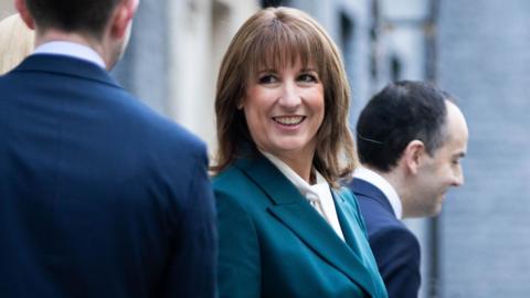 Rachel Reeves on teh day of the budget looking at a colleague whose back is to the camera and she is smiling