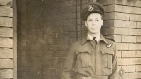Black-and-white archive image of an airman in uniform. He is young and is wearing a cap bearing an emblem.