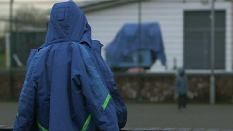 An image of an anonymous child with a hooded coat in a playground