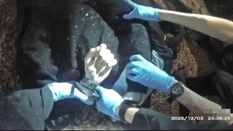 A police image of a man lying on the floor with his hands being handcuffed behind his back.