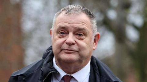 Mike Amesbury arrives at Chester Magistrates' Court ahead of his sentencing hearing on Monday. He wears a dark red tie, white shirt and a dark coat.