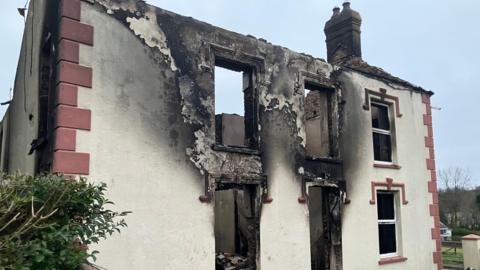 House badly damaged by fire in Drefach, with scorch marks outside some windows and the front door and on the exterior walls