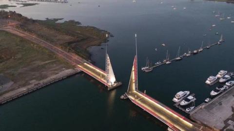 Twin Sails bridge in Poole at night with gold and red lights along its edges 