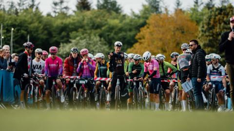 A line up of cyclists in bright lycra at a starting line-up