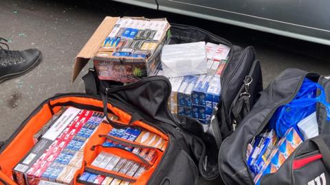 Holdall bags filled with packs of cigarettes and vapes.