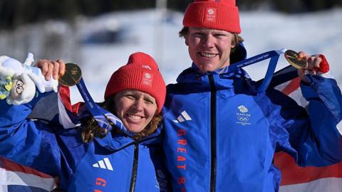 Charlotte Bankes and Huw Nightingale with medals around their necks and holding a union flag