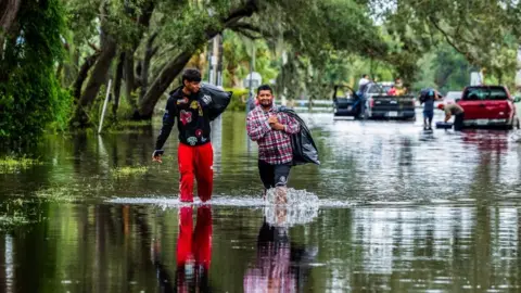 Two people walk through floodwater in North Tampa, Florida