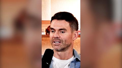 Jimmy Anderson sits behind a microphone