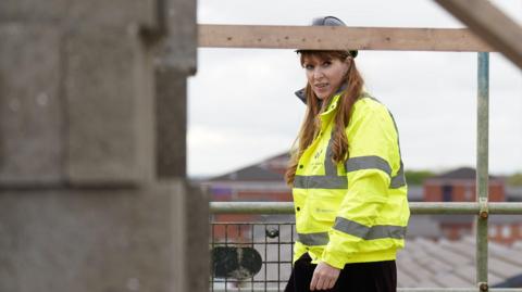 Angela Rayner in high vis and hard hat on a house building site 