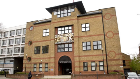 The exterior of St Albans Crown Court, a red-bricked building with a crest and sign reading "Crown Court"