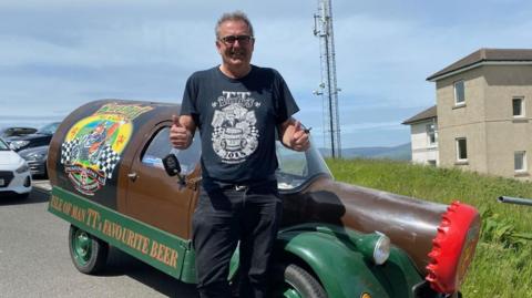 Martin Brunnschweiler stands in front of a beer-bottle shaped van advertising his brewery.