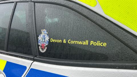 The back window of a Devon and Cornwall Police vehicle. 