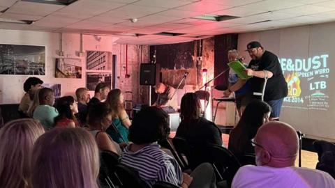 A crowd gathers to watch a spoken word poetry performance at the LTB showrooms in Coventry.