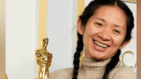 A woman with black hair holding an award.