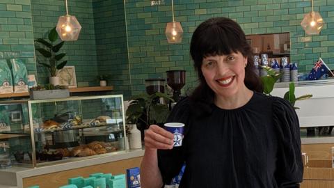 Journalist Zoe Corbyn in a cafe holding a beanless coffee