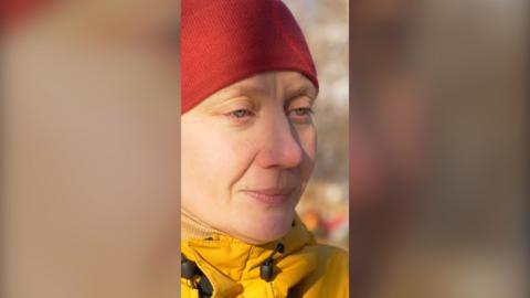 Woman in a red hat and a yellow jacket.