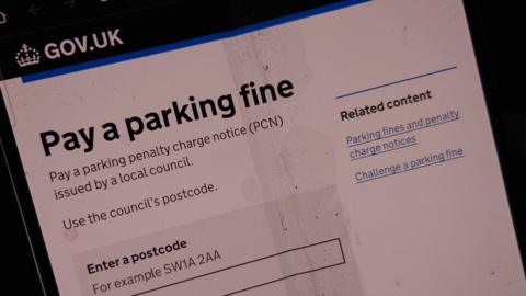 A fake government website. The website appears to be the gov.uk website and uses a similar logo and banner. The site asks the user to pay a parking fine. There is a box where the user can type in their postcode.