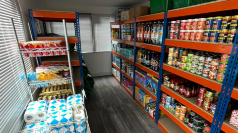 Rows of food items and kitchen rolls are seen on shelves inside the mobile unit.