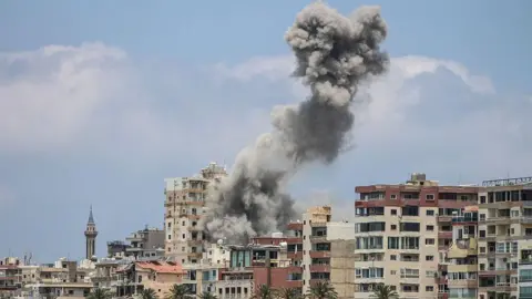 Smoke rises over tyre after a strike on an apartment building by Israel.