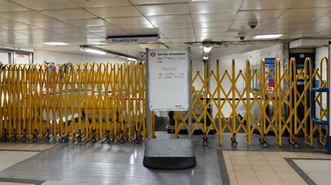 Barriers across the entrance of escalators to the Piccadilly line in a station