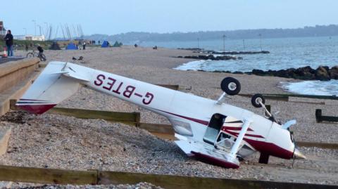 The light aircraft on the beach upside down.