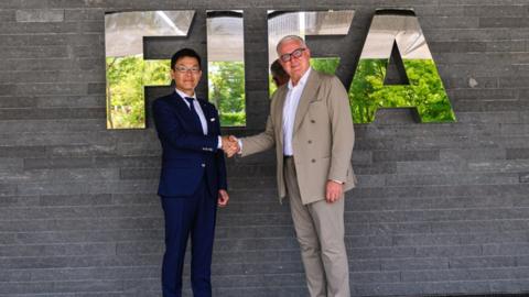 Koji Kobayashi of Konami and Romi Gai of Fifa shake hands, celebrating their new partnership.