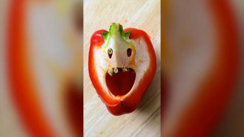 A red pepper cut in half, the inside looks like a human face