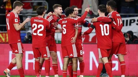 Wales players in red shirts celebrate a goal