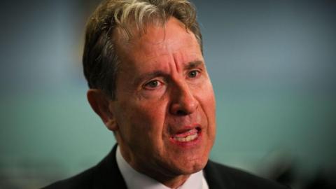 A head and shoulders shot of Dan Norris wearing a white collared shirt beneath a black blazer.