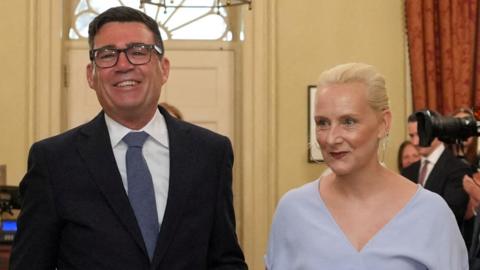 Burnham and van heel walking into No 10 smiling and holding hands.
