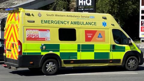 An ambulance seen from the side with flashing blue lights