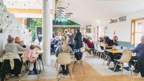 Groups of services users at tables inside Cedarwood Trust
