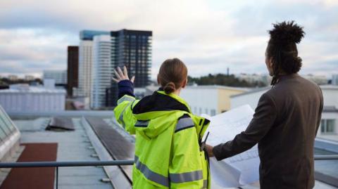 Two people, a woman and man, survey the scene of skyscrapers and other buildings