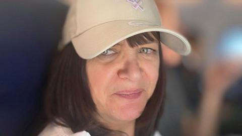 Lindsay Shakeshaft wearing baseball cap and a white t-shirt and smiles into the camera.