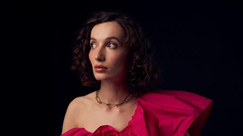 A portrait shot of bestselling Young Adult novelist Bea Fitzgerald wearing a magenta ball gown 